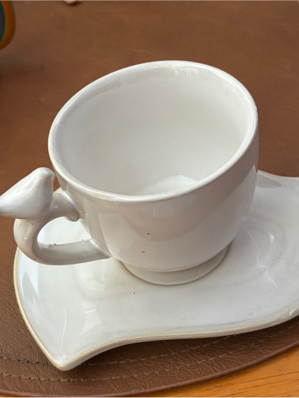 Bird-Handle Cup & Saucer. features a bird-shaped handle and a curved saucer.